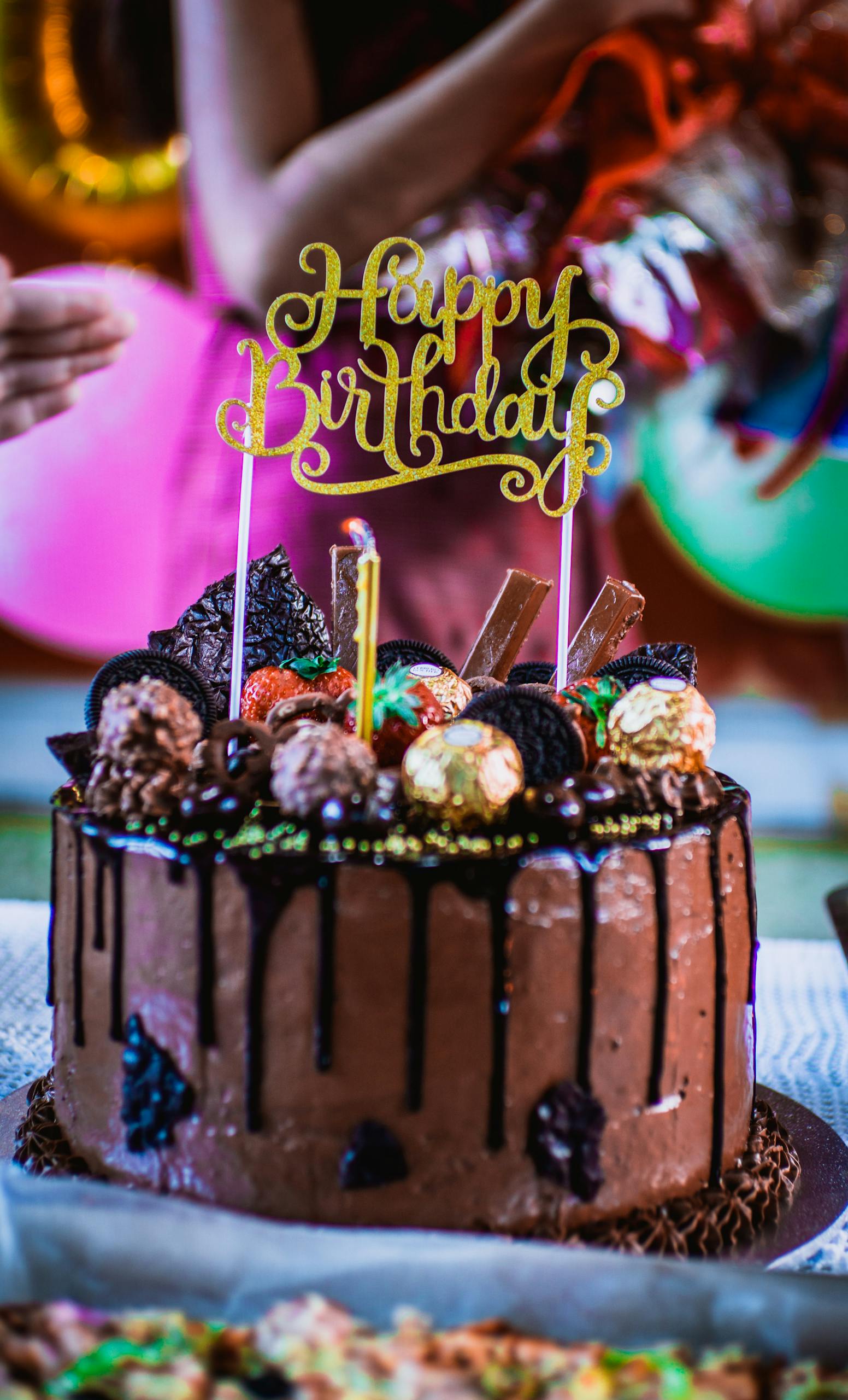 Chocolate birthday cake adorned with candies and Happy Birthday topper.