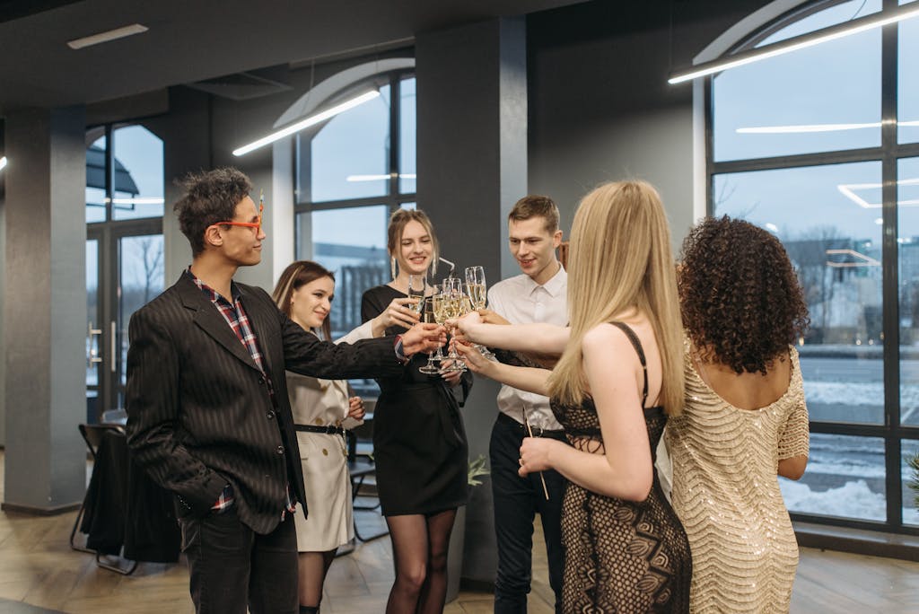 Group of colleagues celebrating indoors by toasting with wine glasses. Diverse office party atmosphere.